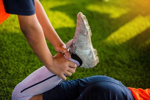 足球运动员抓住脚踝来伸展肌肉 — 图库照片