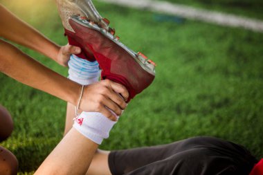 Futbolcu kasları germek için ayak bileği tutuyor