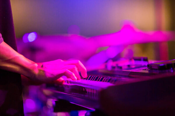 Руки музыканта играют на клавишных на концерте на сцене с b
