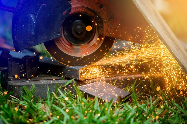 Arbeiter beim Schneiden von Metall mit dem Schleifer auf Rasen im Freien oder constructio — Stockfoto