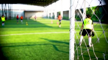 Beyaz goalposts ve kafes ile bulanık hedef futbol kaleci ve futbol oyuncu topa vurmaya eğitimi vardır. Futbol Akademisi.