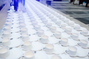 Beyaz masada bir sürü beyaz kahve bardağı