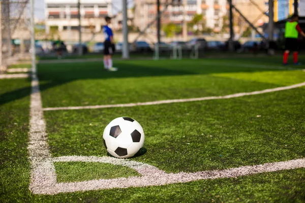Футбольный мяч на зеленой искусственной территории на углу футбольного поля — стоковое фото