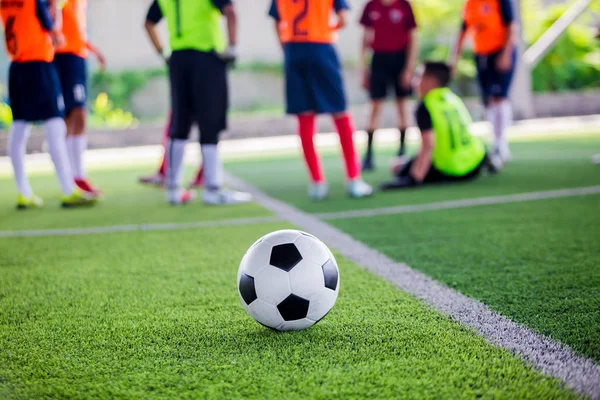 Pallone da calcio su tappeto erboso artificiale verde con giocatori di calcio sfocati — Foto Stock