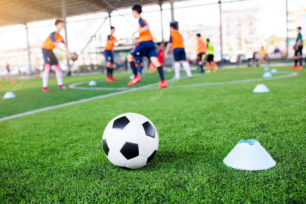 football between marker cones on green artificial turf with blur