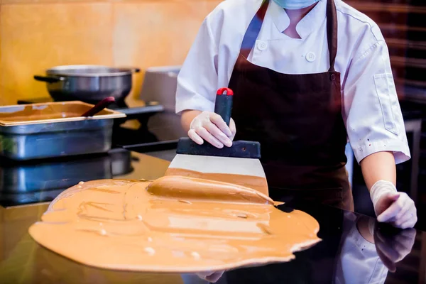 cook woman is mixing chocolate cream with professional chocolate