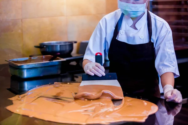 cook woman is mixing chocolate cream with professional chocolate