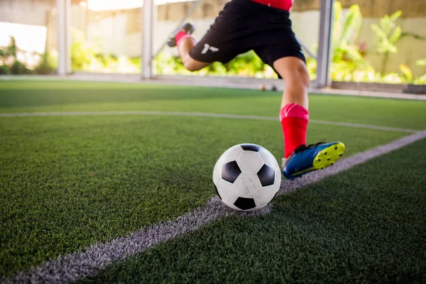 Soccer player speed run to shoot ball to goal on artificial turf