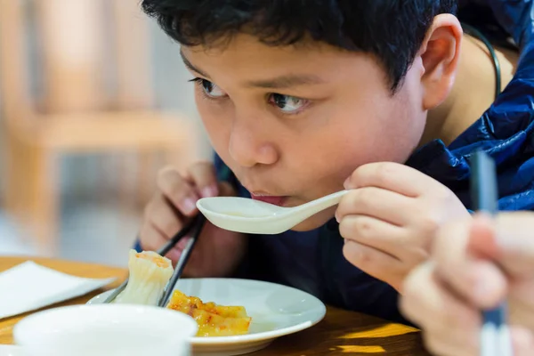 Il ragazzo sta mangiando cibo cinese . — Foto Stock