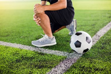 Futbolcu ile yeşil suni çim üzerinde Futbol topu oturuyor 