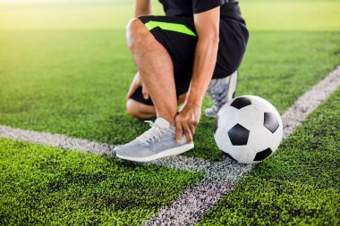Futbolcu ile yeşil suni çim üzerinde Futbol topu oturuyor 