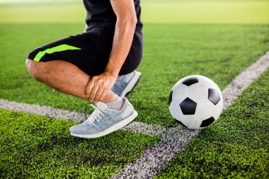 Futbolcu ile yeşil suni çim üzerinde Futbol topu oturuyor 