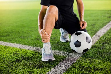 Futbolcu ile yeşil suni çim üzerinde Futbol topu oturuyor 
