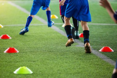 çocuk futbolcular Jogging ve gree koni işaretleri arasında atlamak