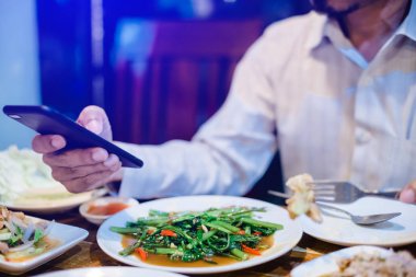 man is eating along with playing smartphone. Lifestyle in today'