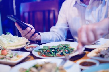 man is eating along with playing smartphone. Lifestyle in today'