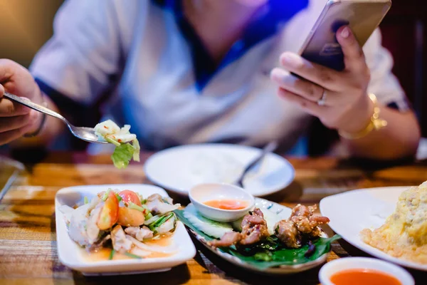 Woman is eating along with playing smartphone. Lifestyle in toda