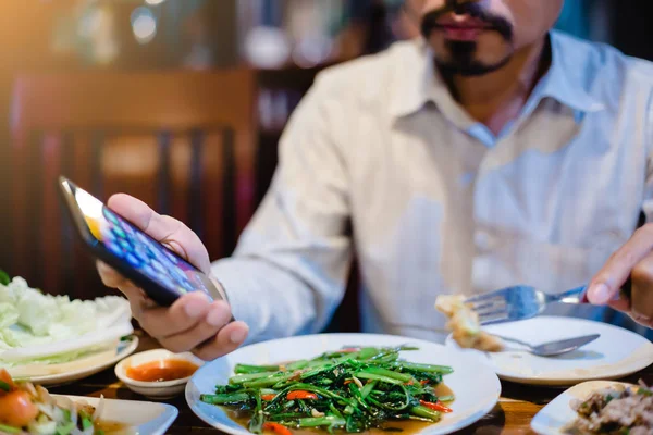 man is eating along with playing smartphone. Lifestyle in today\'
