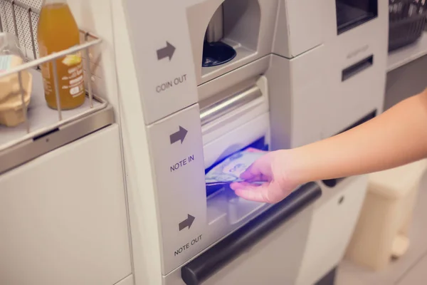 The child hand is picking up banknotes from the automatic paymen