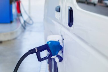 Benzin istasyonunda ki beyaz minibüsü yakıtla dolduruyor. Petrol a