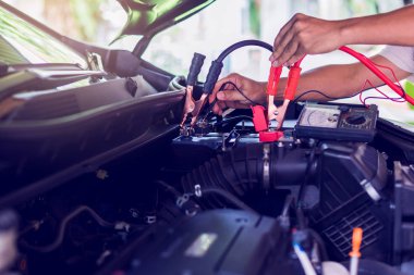 Oto tamircisi araç meyilli voltaj seviyesini kontrol etmek için voltmetre kullanın