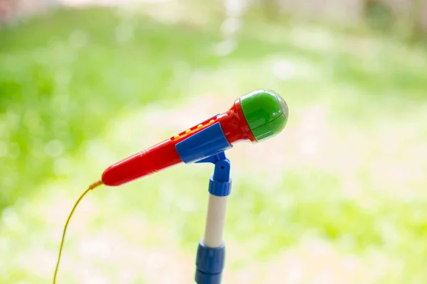 Foco seletivo para microfone de brinquedo colorido em verde embaçado de volta — Fotografia de Stock