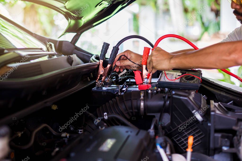 Auto mechanic use voltmeter to check voltage level in car batter