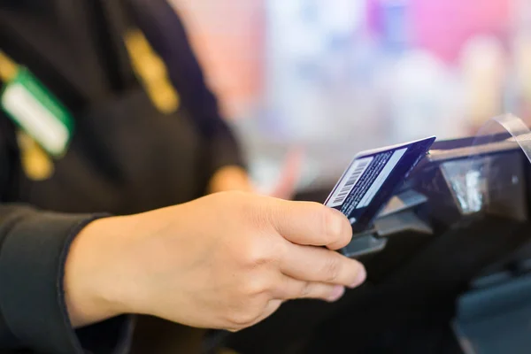 Selective focus to the cashier is swiping the credit card or mem