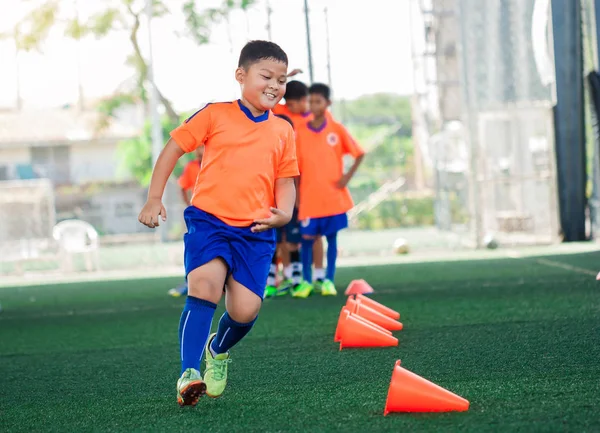 Giocatore di calcio bambino Jogging e saltare tra marcatori cono sul verde — Foto Stock
