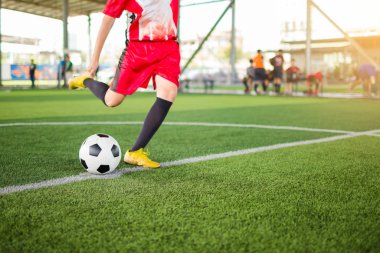 çocuk futbolcu hız bulanık futbolcu arka plan ile yapay çim üzerinde hedefe topu ateş etmek için çalıştırın. Futbol akademisinde futbolcu eğitimi.