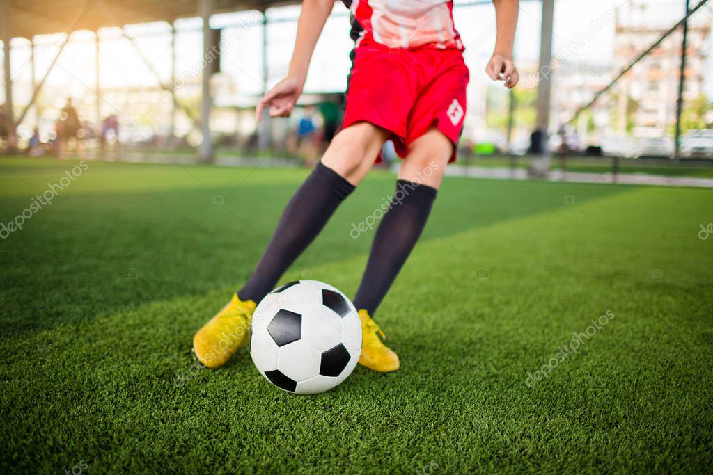 kid soccer player speed run to shoot ball to goal on artificial turf with blurry soccer player background. Soccer player training in football academy.