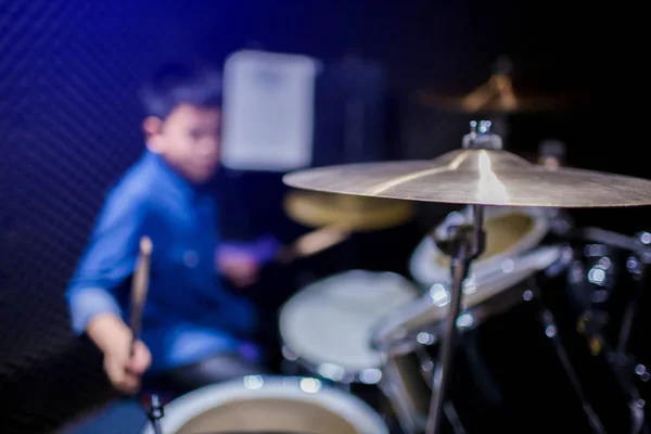 Selective focus to cymbals of drum set with blurry kid learning and play drum set with teacher in music room. The concept of musical instrument.