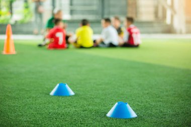 mavi marker konileri için seçici odak bulanık çocuk oyuncular eğitim arka plan ile yeşil yapay çim futbol eğitim ekipmanları vardır. futbol akademisi eğitim sınıfı için malzeme.