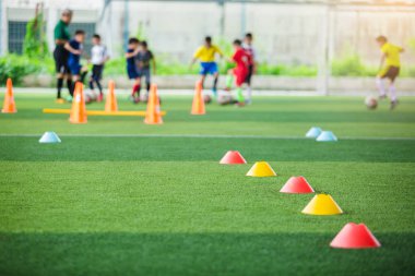 kırmızı ve sarı marker konileri için seçici odak bulanık çocuk oyuncular eğitim arka plan ile yeşil yapay çim futbol eğitim ekipmanları vardır. futbol akademisi eğitim sınıfı için malzeme.