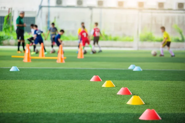 kırmızı ve sarı marker konileri için seçici odak bulanık çocuk oyuncular eğitim arka plan ile yeşil yapay çim futbol eğitim ekipmanları vardır. futbol akademisi eğitim sınıfı için malzeme.