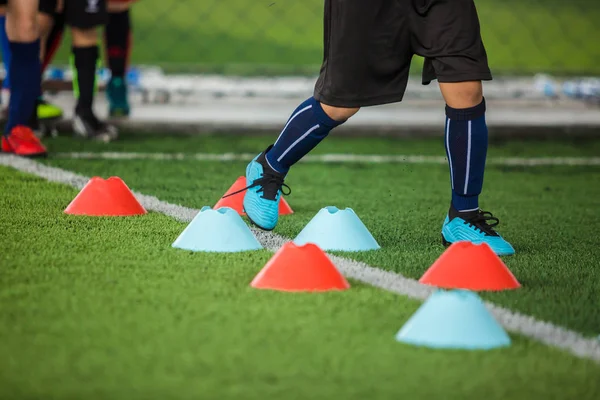 Pemain sepak bola anak berlari di antara penanda kerucut pada artifisial hijau — Stok Foto