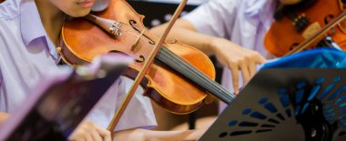 Asyalı erkek öğrenciler gro müzik gösterimi ile keman çalıyor