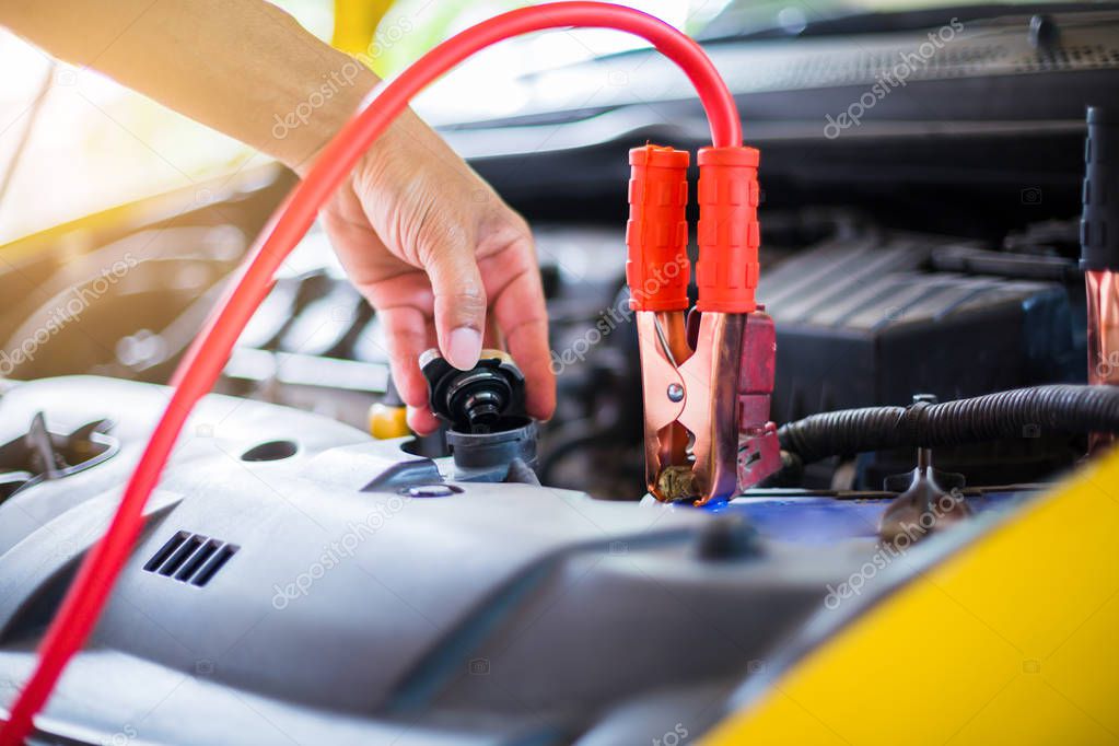 Hands of mechanic check water in car radiator and charging car b