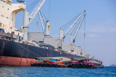 Malları vinçle kargo gemisine yüklüyorlar. Bir tüccardan teslimat.
