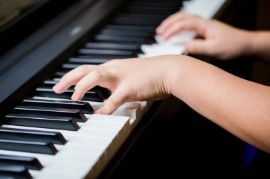 Piyano çalmak için çocuk parmaklarına ve piyano tuşuna özen göster. Konser için müzik aleti ya da öğrenme müziği var. Sahnede piyano çalan çocuk müzisyenin eli kapalı..