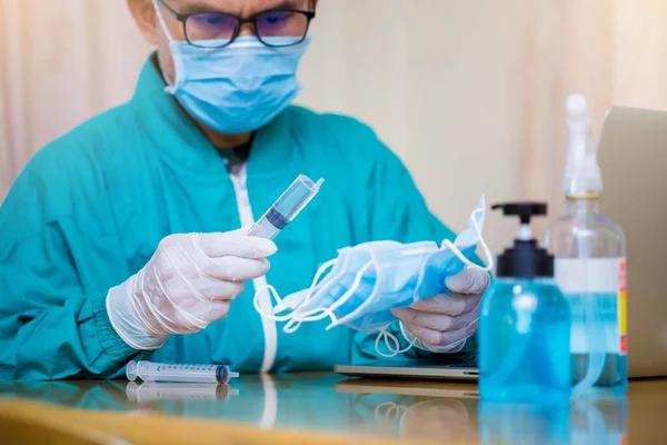 Medical doctor / psychologist working with laptop in the laboratory. Coronavirus Covde19 vaccine research concept. Doctor wear mask, carry test tubes and many masks.