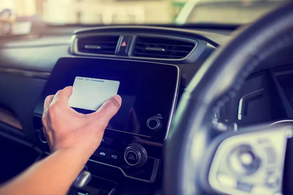 Selective focus to black smart monitor screen at the console with blur  driver's hand holds a smart card to read information in the car.