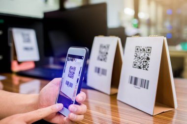 El ele tutuşan bir telefon ve QR kodunu tarıyorum. Adamın biri QR kodu ile ödeme yapıyor. Müşteri ödemeyi akıllı telefon ve tarama koduyla yapıyor. Seçici odak.
