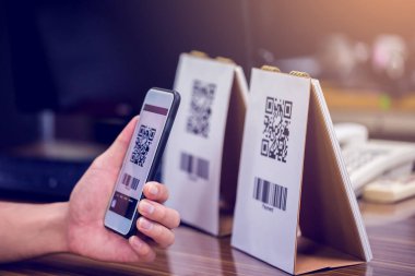 El ele tutuşan bir telefon ve QR kodunu tarıyorum. Adamın biri QR kodu ile ödeme yapıyor. Müşteri ödemeyi akıllı telefon ve tarama koduyla yapıyor. Seçici odak.