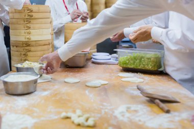 Aşçılar Çin mantılarını geleneksel bambu buharlı tencerelerle bir restoranda pişiriyorlar. Dim Sum şefleri Tayvan 'daki ünlü restoranda hamur işi paketliyor..