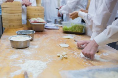Aşçılar Çin mantılarını geleneksel bambu buharlı tencerelerle bir restoranda pişiriyorlar. Dim Sum şefleri Tayvan 'daki ünlü restoranda hamur işi paketliyor..