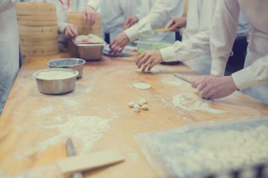 Aşçılar Çin mantılarını geleneksel bambu buharlı tencerelerle bir restoranda pişiriyorlar. Dim Sum şefleri Tayvan 'daki ünlü restoranda hamur işi paketliyor..