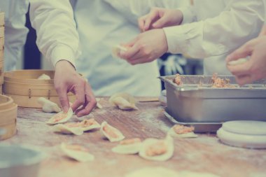 Aşçılar Çin mantılarını geleneksel bambu buharlı tencerelerle bir restoranda pişiriyorlar. Dim Sum şefleri Tayvan 'daki ünlü restoranda hamur işi paketliyor..