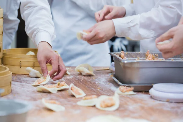 Aşçılar Çin mantılarını geleneksel bambu buharlı tencerelerle bir restoranda pişiriyorlar. Dim Sum şefleri Tayvan 'daki ünlü restoranda hamur işi paketliyor..