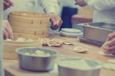 Aşçılar Çin mantılarını geleneksel bambu buharlı tencerelerle bir restoranda pişiriyorlar. Dim Sum şefleri Tayvan 'daki ünlü restoranda hamur işi paketliyor..